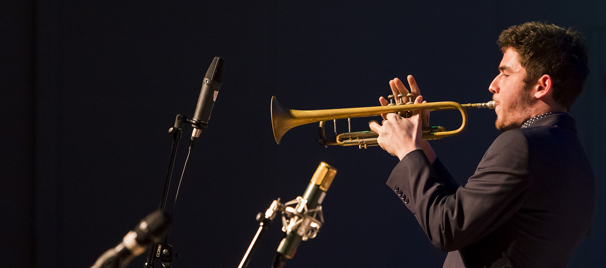 Trumpet player in a black suit performs a solo during an event